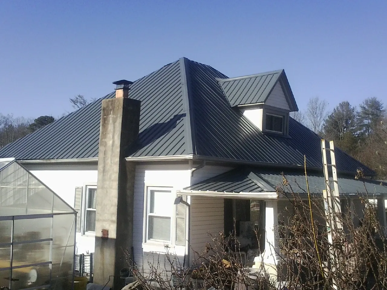 Dark blue standing seam metal roof on a white farmhouse with dormer — Slate & Tile Roof Repair by Roofing Brothers in Santee