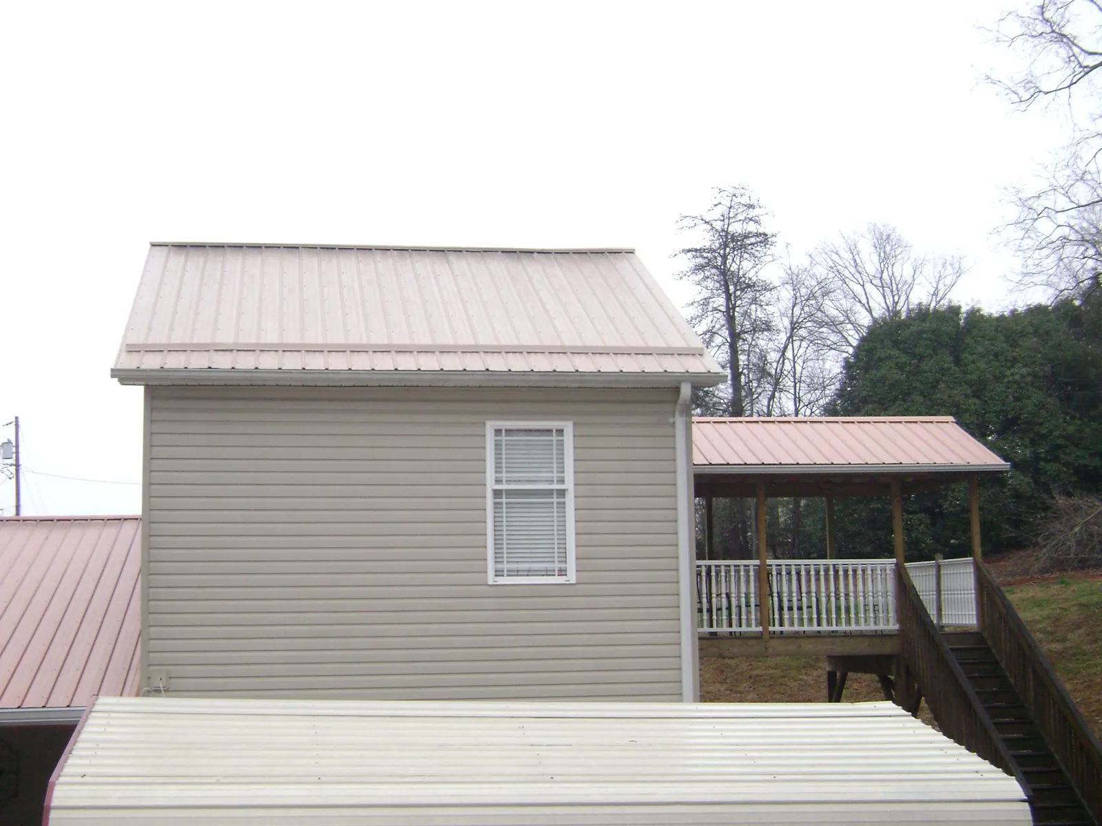 Tan metal roofs on a two story addition and attached porch, from a Roof Replacement job in Santee